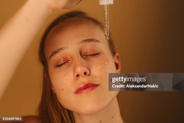 beauty routine of a young woman - facial oil stock pictures, royalty-free photos & images
