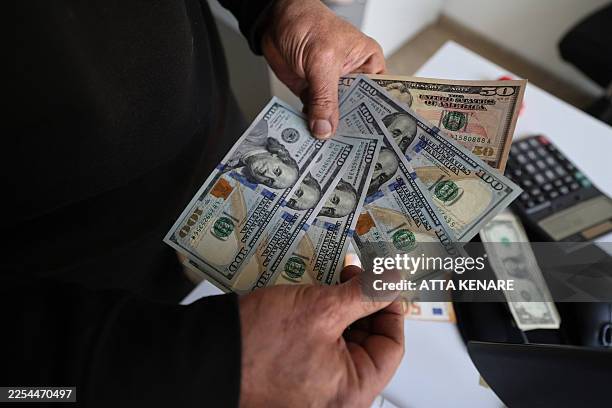 An Iranian man shows US dollar banknotes in Tehran on January 7, 2026. Iran's economy has been hit hard by tough international sanctions, with the...