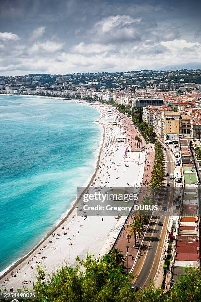 coastline curving along promenade des anglais, overlooking crowded beach and turquoise mediterranean sea from nice, france - alpes maritimes stock pictures, royalty-free photos & images