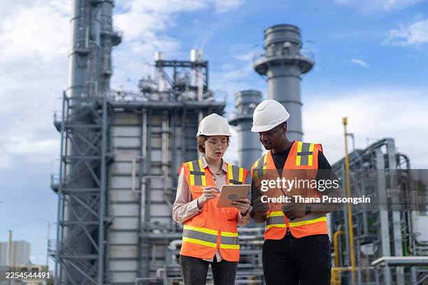 male and female engineers work using laptop and tablet in gas refineries - oil refinery engineer stock pictures, royalty-free photos & images