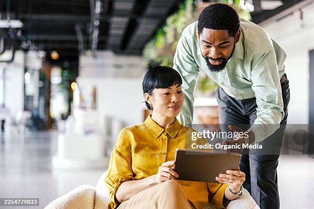 diverse coworkers collaborating on digital tablet in modern office - shared vision stock pictures, royalty-free photos & images