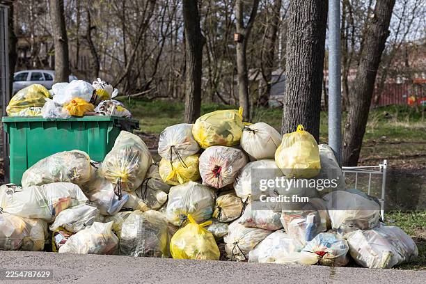 overfilled dustbin and lots of garbage bags - müllcontainer stock-fotos und bilder