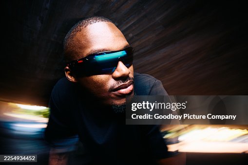 Close up action shot of male runner with sunglasses leaning forward in backlit underpass, motion blur Close up action shot of male runner with sunglasses leaning forward in backlit underpass, motion blur