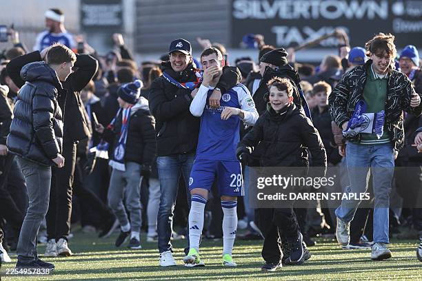 Macclesfield's English midfielder James Edmondson is surrounded by supporters after they storm the pitch to celebrate the team's victory at the end...