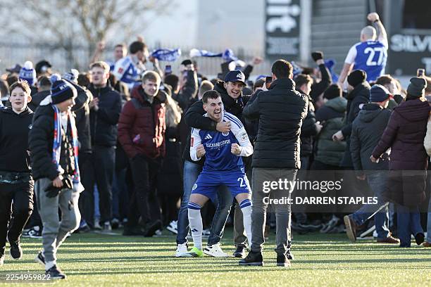 Macclesfield's English midfielder James Edmondson is surrounded by supporters after they storm the pitch to celebrate the team's victory at the end...