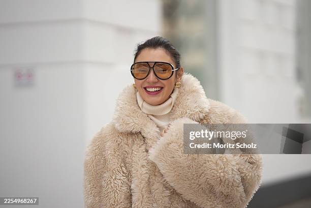 Milena Kar is seen wearing a beige shearling jacket with a voluminous oversized silhouette, soft curly texture, wide sleeves from Ducie London; a...