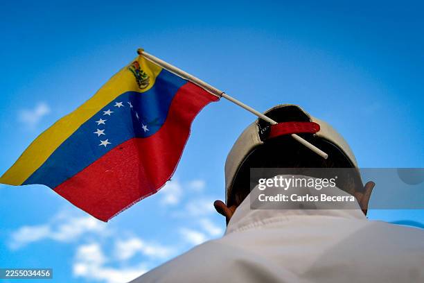 Man carries a Venezuelan flag during a demonstration in support of former Venezuelan President Nicolás Maduro on January 10, 2026 in Caracas,...