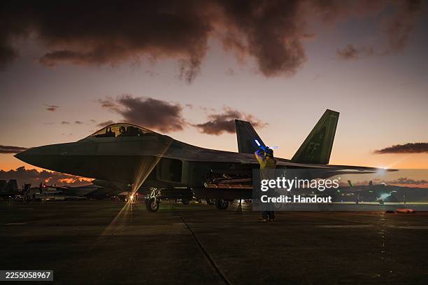 In this handout photo from the U.S. Air Force, a U.S. Air Force crew chief guides in an F-22 Raptor following a large-scale strike against Venezuela...