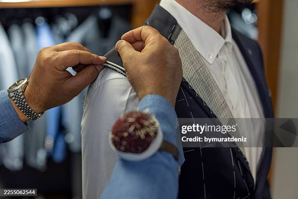 tailor pinning mens suit jacket during custom fitting session - fashion stylist stock pictures, royalty-free photos & images