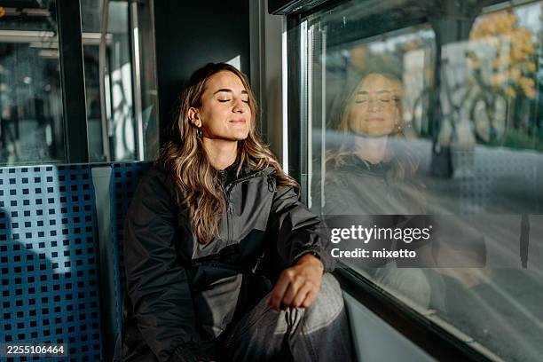 junge, schöne frau, die sich entspannt, während sie im zug fährt - hauptverkehrszeit stock-fotos und bilder