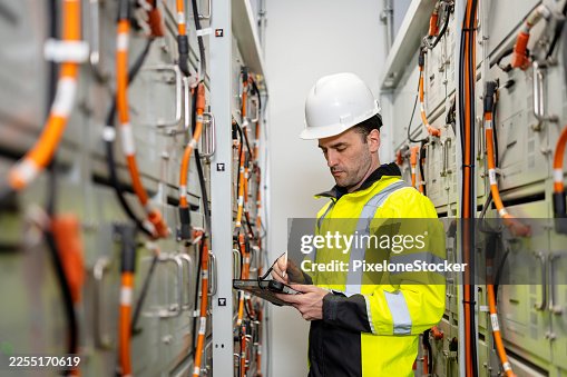Electrical Engineer or Technician performs routine checks on battery connections in a battery storage control room are essential for safety and performance. Electrical Engineer or Technician performs routine checks on battery connections in a battery storage control room are essential for safety and performance.