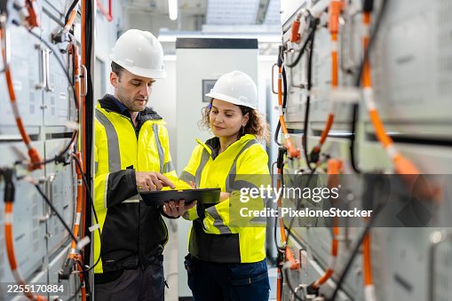Electrical Engineer or Technician team performs routine checks on battery connections in a battery storage control room are essential for safety and performance. Electrical Engineer or Technician team performs routine checks on battery connections in a battery storage control room are essential for safety and performance.