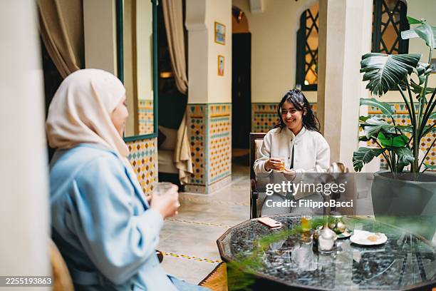 two women enjoying hot arabian tea in a cafe - moroccan culture stock pictures, royalty-free photos & images