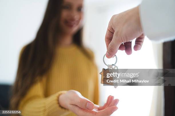 woman receiving the key to her new home in bright living room - tenant stock pictures, royalty-free photos & images