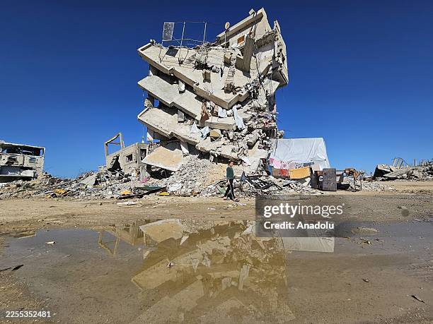 Girl is seen in front of a damaged five-story building, which is on the verge of collapse, in the Ketibe neighborhood of Khan Yunis in the southern...