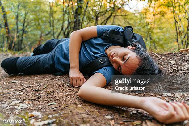 unconscious injured female hiker lying on the ground in the mountain - unconscious stock pictures, royalty-free photos & images