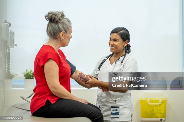 friendly nurse measures blood pressure for patient in clinic, highlighting care and diversity - phonendoscope stock pictures, royalty-free photos & images