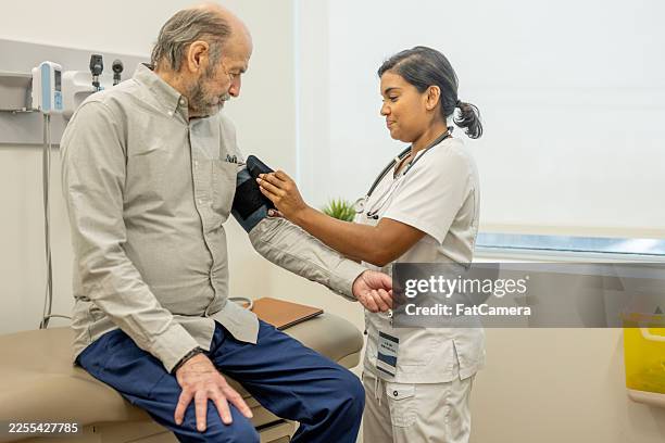 compassionate nurse checks blood pressure of elderly man during clinic visit - phonendoscope stock pictures, royalty-free photos & images