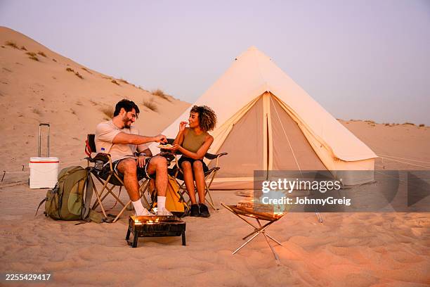couple glamping in desert enjoying campfire and food - table for two stock pictures, royalty-free photos & images