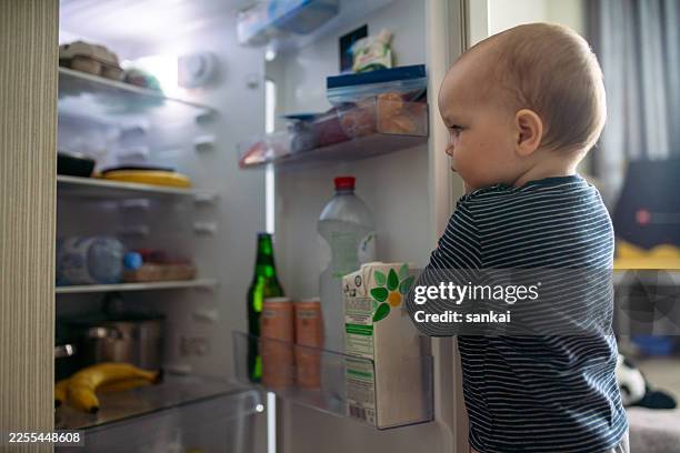 adorable baby exploring an open refrigerator at home with curious expression - mini fridge stock pictures, royalty-free photos & images