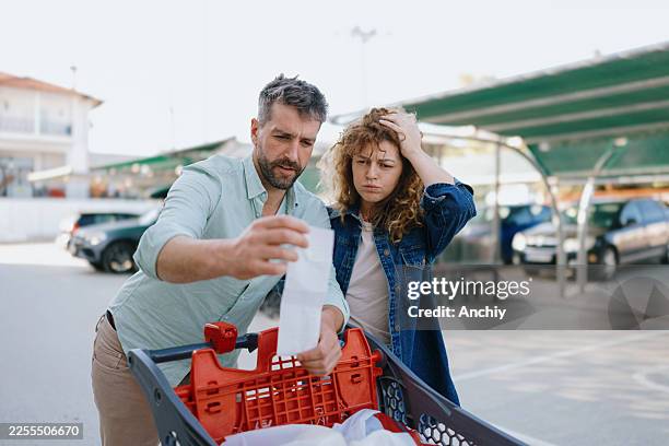 couple shocked by grocery costs - overloaded shopping cart stock pictures, royalty-free photos & images