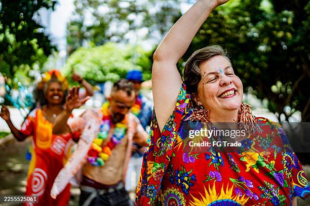 excited senior woman dancing and enjoying carnival outdoors - street party stock pictures, royalty-free photos & images