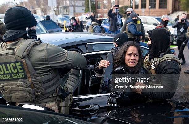 Agents detain a woman after pulling her from a car on January 13, 2026 in Minneapolis, Minnesota. The Trump administration has deployed over 2,400...