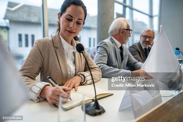 woman writing notes during political conference meeting - formalwear stock pictures, royalty-free photos & images