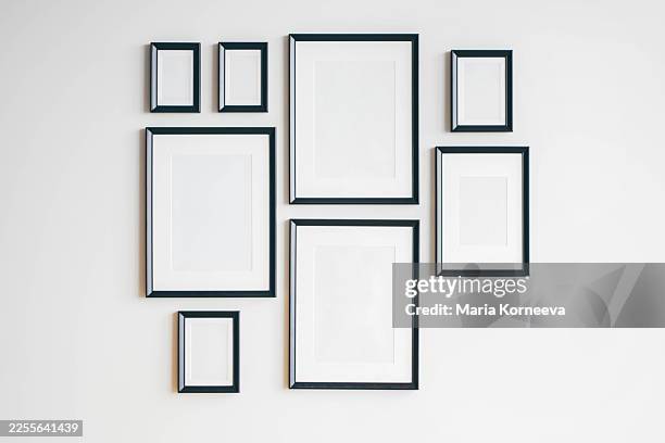 multiple many black picture frames on white wall. - wall framing stock pictures, royalty-free photos & images