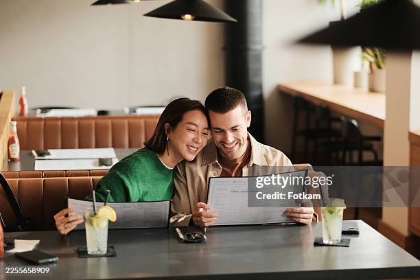 joyful married couple enjoying a warm dining experience at a modern restaurant - ordering dinner stock pictures, royalty-free photos & images