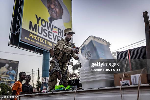 Ugandan police officer unloads ballot boxes from a truck at a polling station set up in front of an electoral billboard supporting Uganda's incumbent...