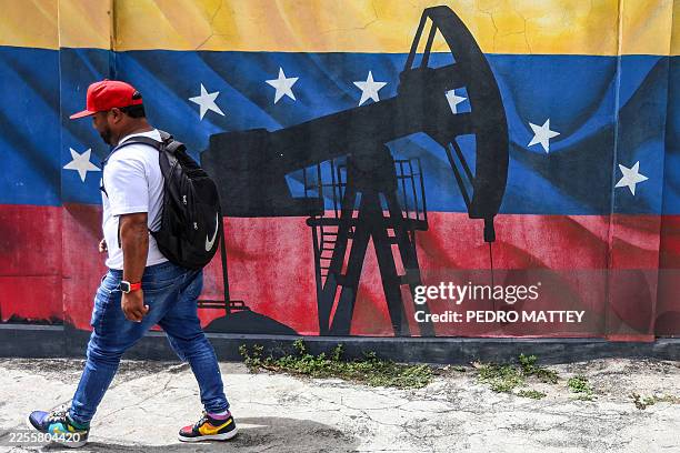 Man walks past a mural depicting an oil pumpjack on a Venezuelan flag in Caracas on January 15, 2026. Venezuelan opposition leader Maria Corina...