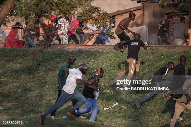 Pedestrians flee as military police intervene, on the sidelines of votes being counted at a polling station in Kampala on January 15 during Uganda's...