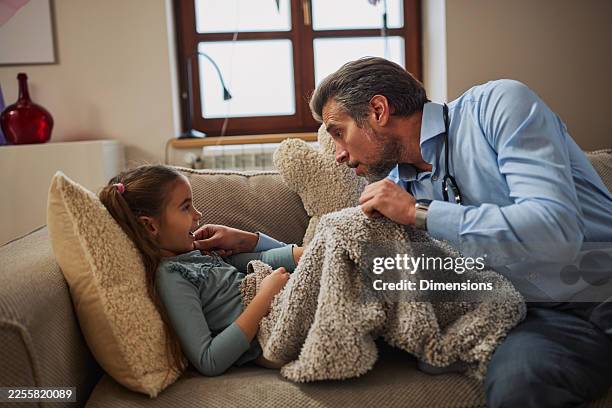 doctor visits sick girl at home, offering comfort and care on a cozy couch - phonendoscope stock pictures, royalty-free photos & images