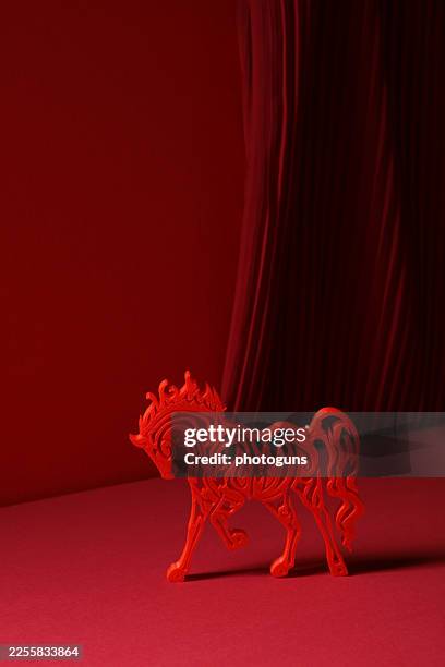 Red stylized horse silhouette against a minimalist background with red pleated fabric. Chinese New Year 2026 symbol.