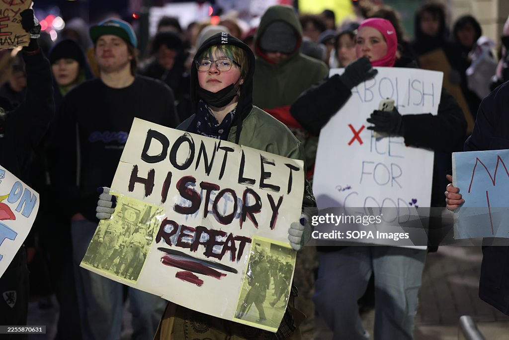 Anti-ICE demonstrators hold placards as they march from the