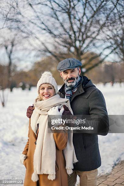 happy couple enjoying winter walk in snowy park - sjaal stockfoto's en -beelden