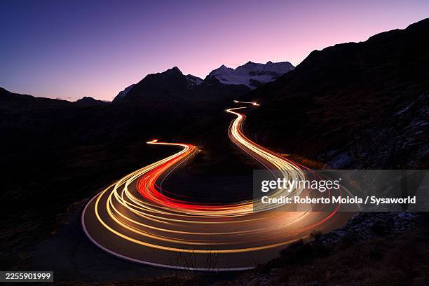 car trai lights on bernina pass road - light trail stock pictures, royalty-free photos & images