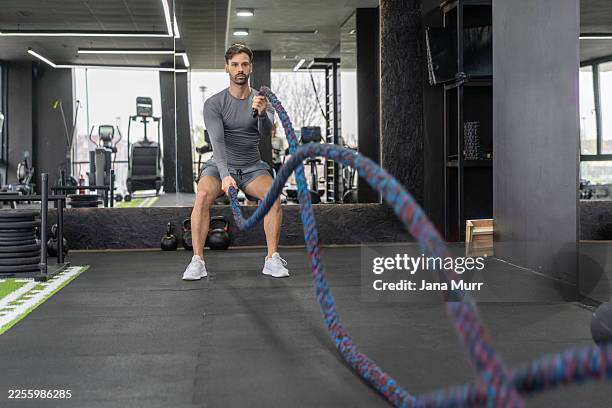 athlete engaging in high-intensity rope workout routine - battle rope stock pictures, royalty-free photos & images