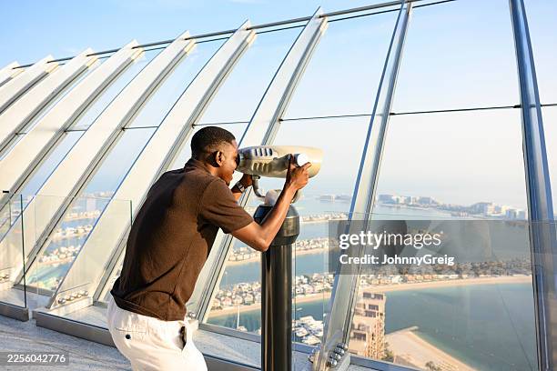 man looking at palm jumeirah through observation binoculars - the bigger picture stock pictures, royalty-free photos & images
