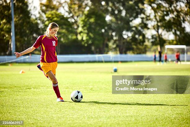 confident girl kicking soccer ball on field - team sport stock pictures, royalty-free photos & images