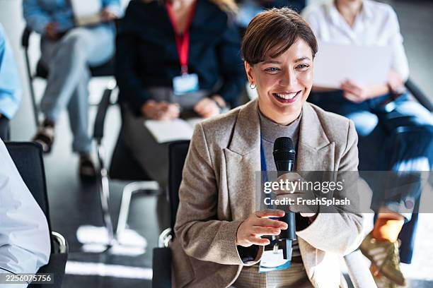 confident woman speaks into microphone during panel discussion at conference networking event - spokesperson stock pictures, royalty-free photos & images