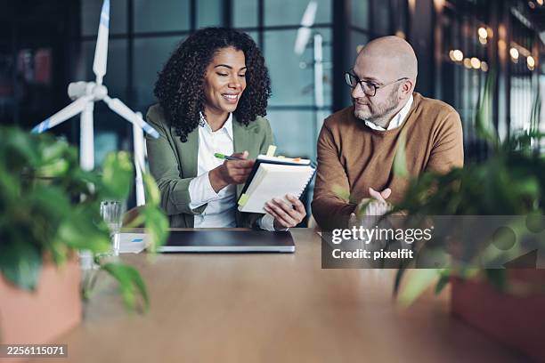couple of business people sitting side by side and discussing environmental issues - social responsibility stock pictures, royalty-free photos & images
