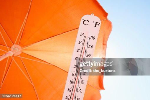 Thermometer against orange parasol, sky and sun Thermometer against orange parasol, sky and sun