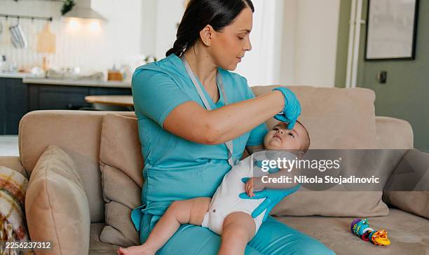 pediatra haciendo una medición rutinaria de la temperatura corporal de un niño. - achatar la curva de epidemia fotografías e imágenes de stock