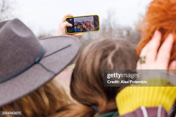 écran de smartphone montrant un selfie d’une mère, de sa fille et d’une amie lors d’un voyage dans les poconos, en pennsylvanie. la vue par-dessus l’épaule se concentre sur le souvenir partagé. - vue de par dessus lépaule photos et images de collection
