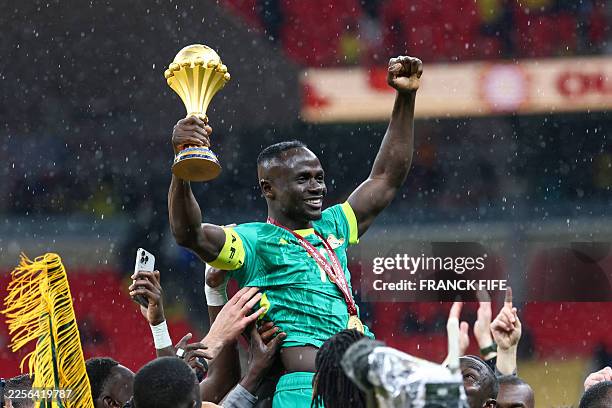 Senegal's forward Sadio Mane holds up the trophy as he celebrates with his teammates after winning the Africa Cup of Nations final football match...