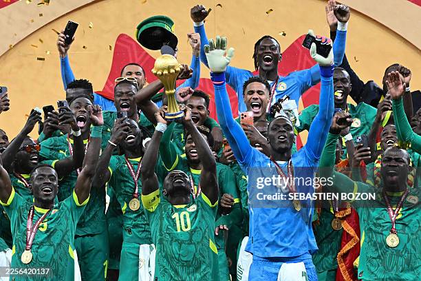 Senegal's forward Sadio Mane holds up the trophy as he celebrates with his teammates after winning the Africa Cup of Nations final football match...