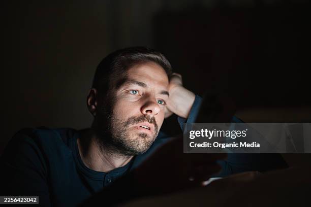 man using smartphone in dark bedroom at night - phone screen reflection stock pictures, royalty-free photos & images
