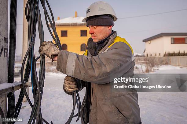 An electrician from DTEK, the Ukrainian energy company, inspects electrical cables during repairing on an electricity pylon on January 14, 2026 in...